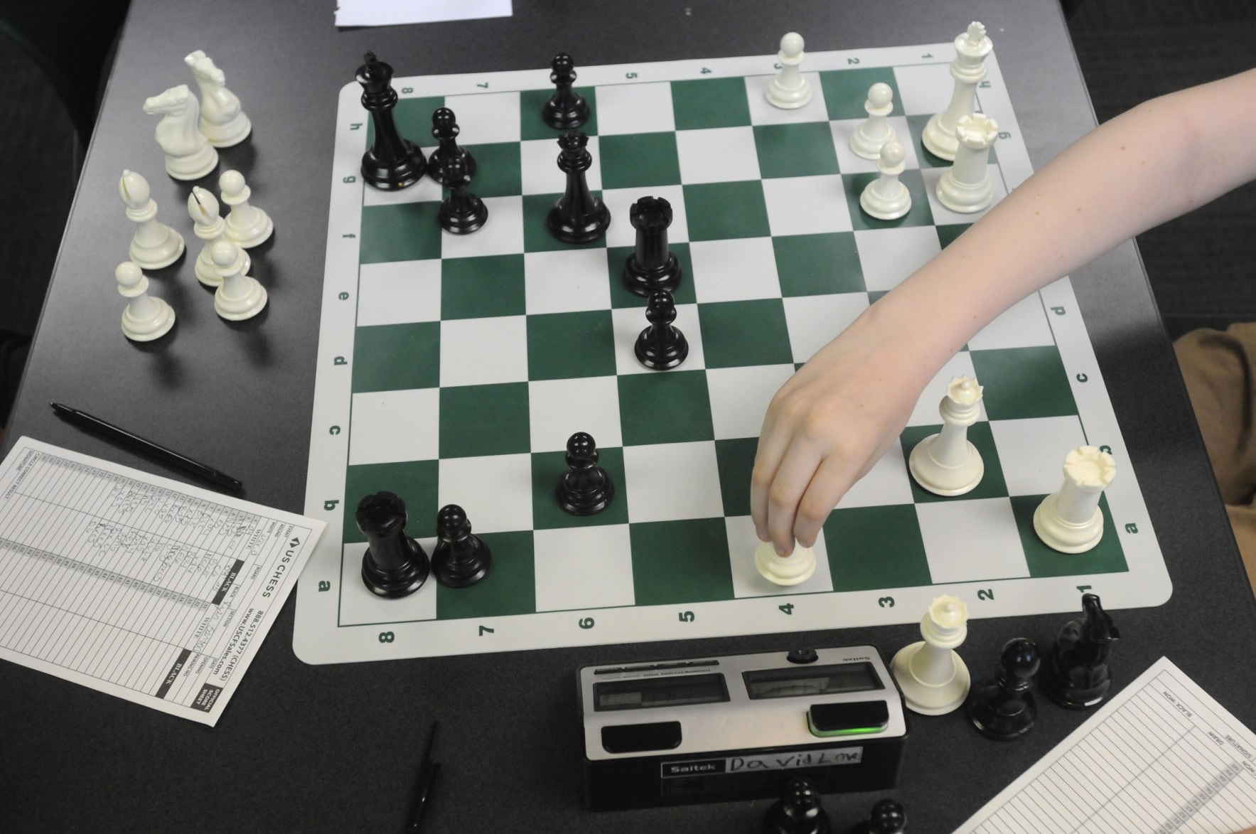 Young students intently playing chess at a library tournament, focused on their boards.
